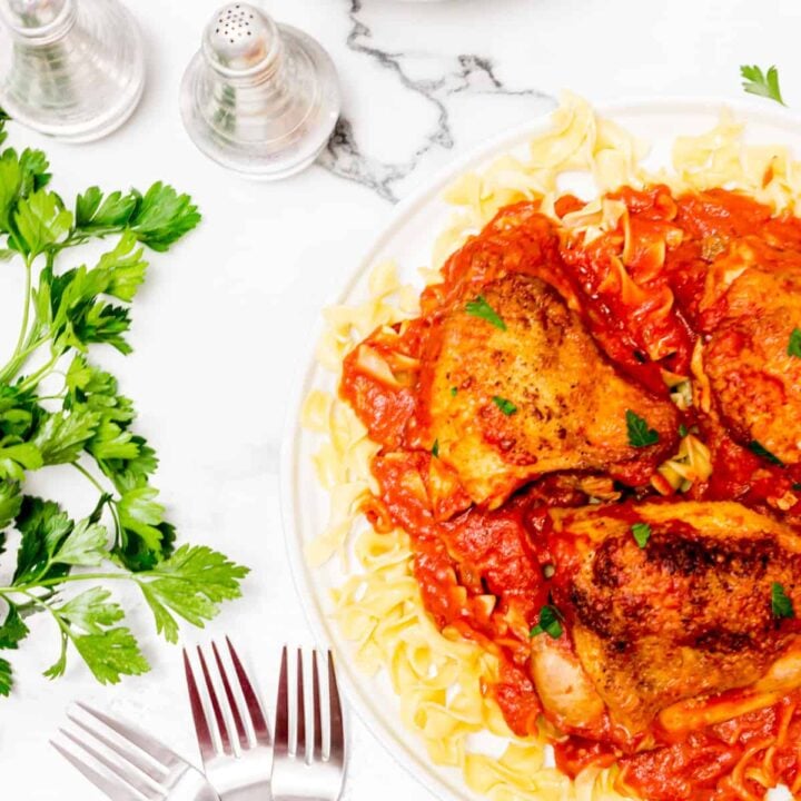 Plate of spicy chicken on bed of pasta.