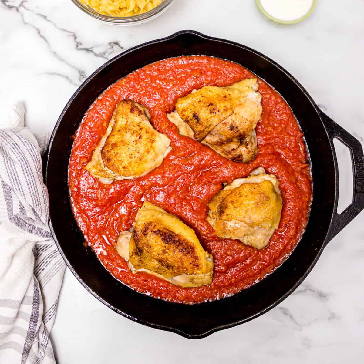 Tomato sauce and chicken cooking in skillet.