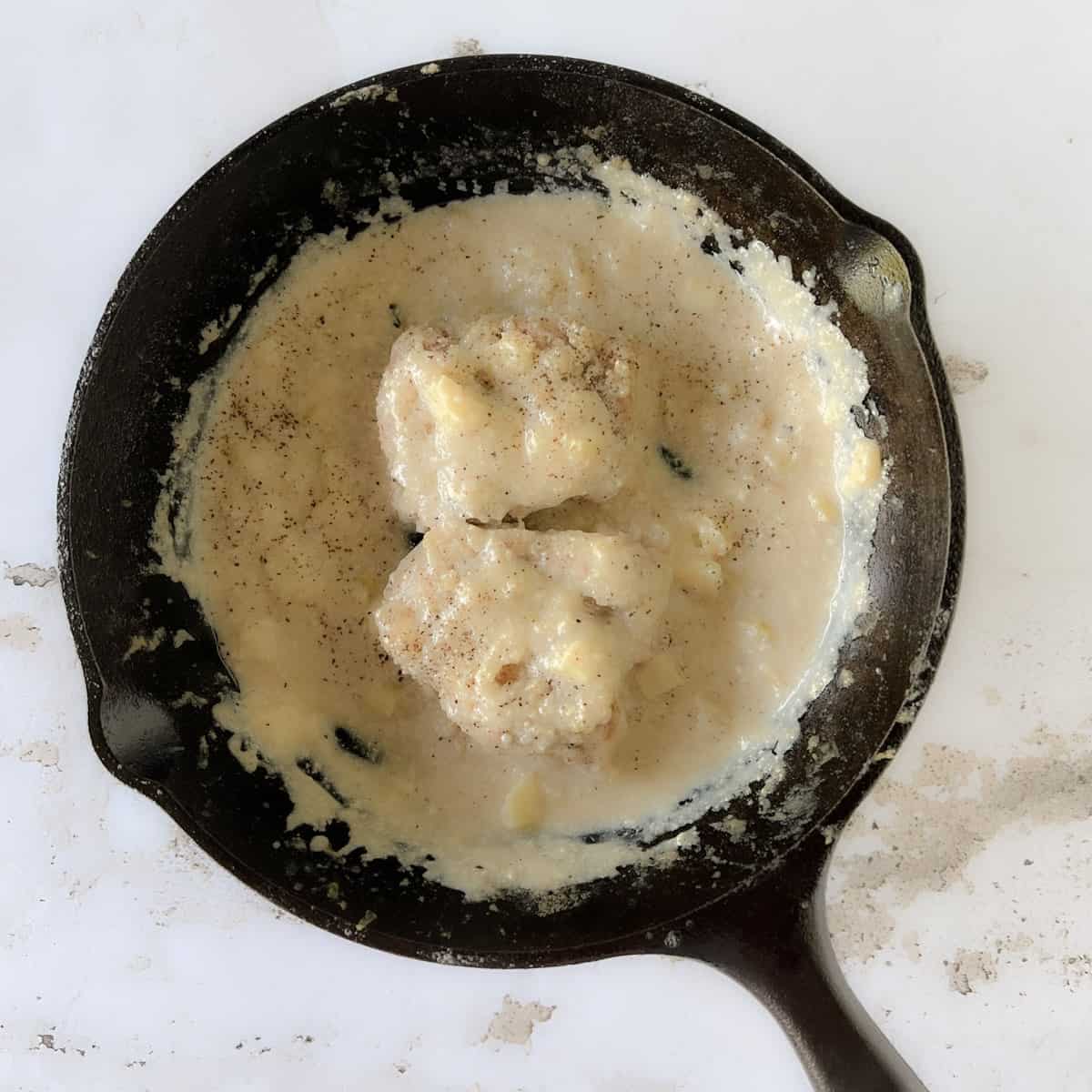 chicken thigh in a creamy garlic sauce in small cast iron skillet.