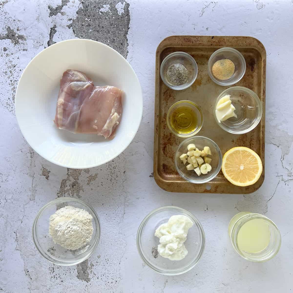 ingredients to make garlic chicken measured out on a textured surface.