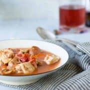 bowl of checken stew in blue rimmed plate and striped nakin on table.