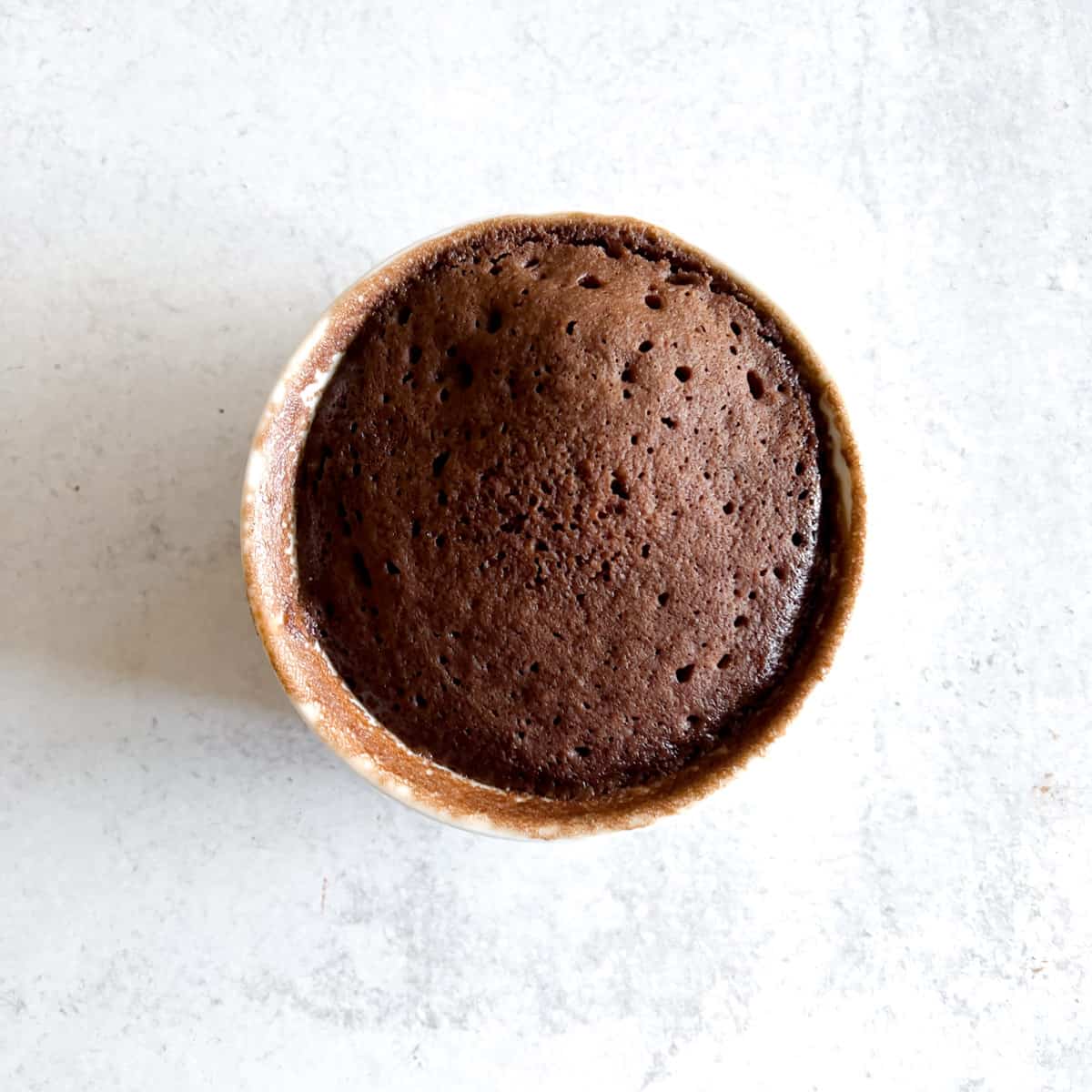 small baked chocolate cake in white ramekin.