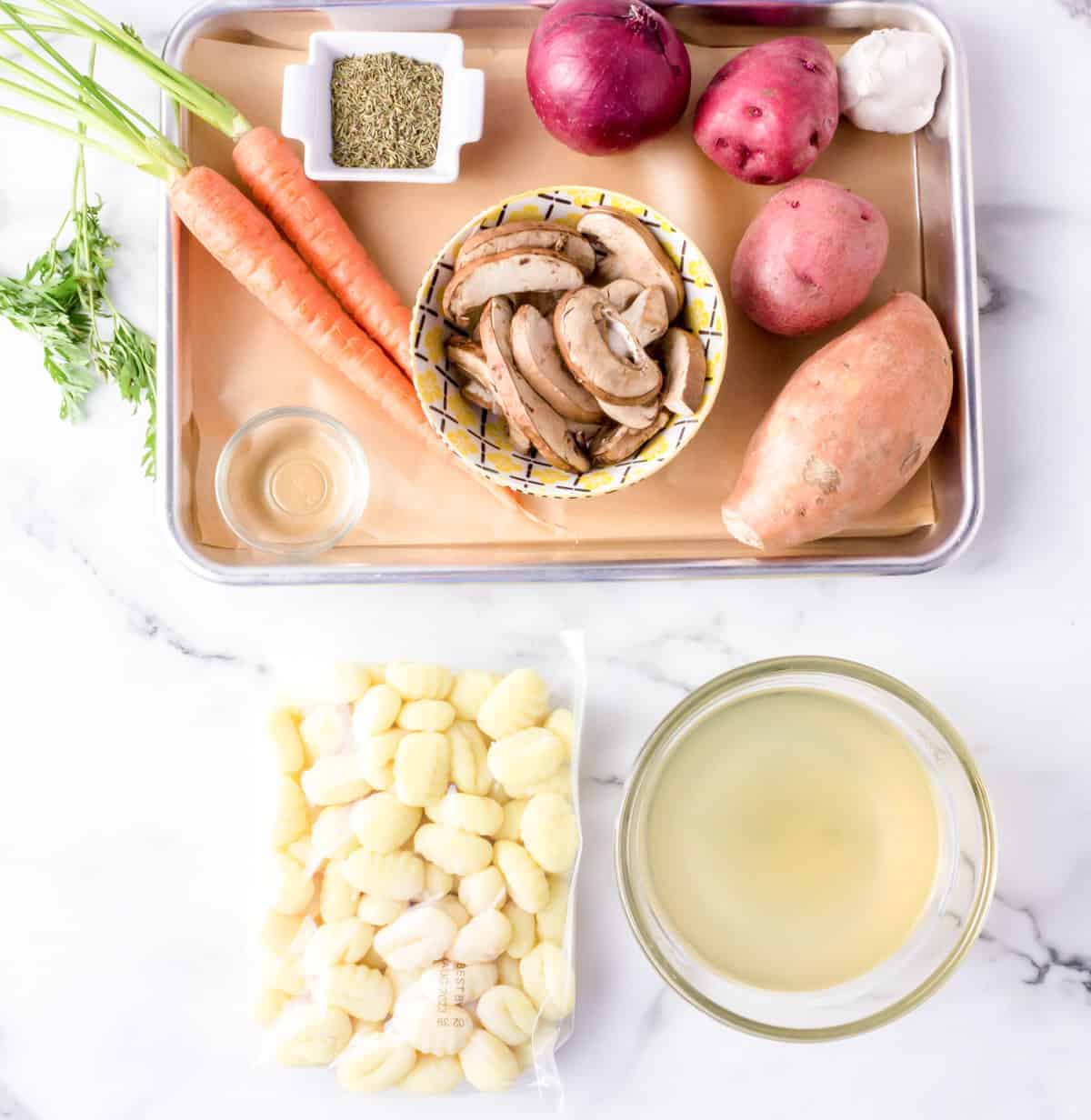 Carrots, mushrooms, potatoes and spices on a roasting pan.