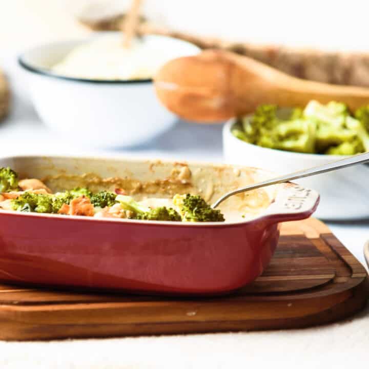 Baked chicken divan in small baking dish on wooden board.