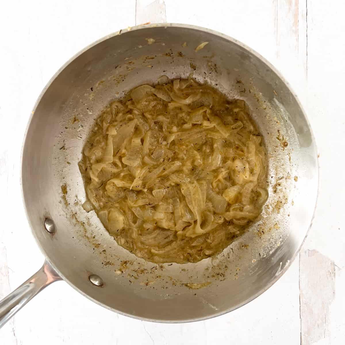 Onion and wine cooking in a stainless steel saucepan.