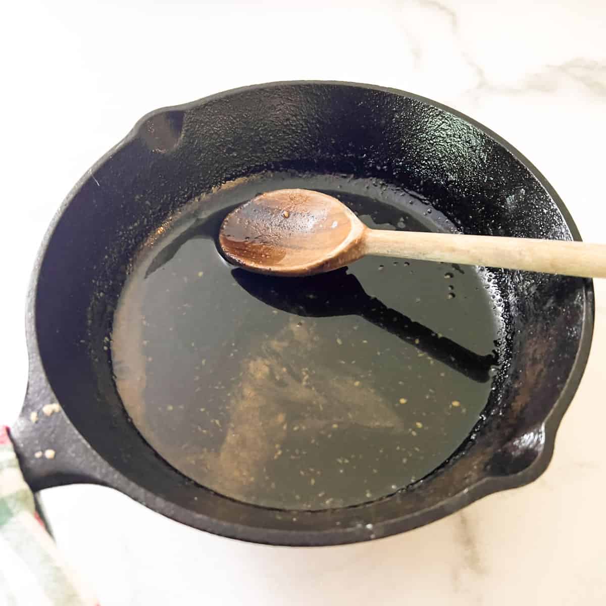 Water, brown sugar and mustard mixed and cooking in small cast iron skillet.