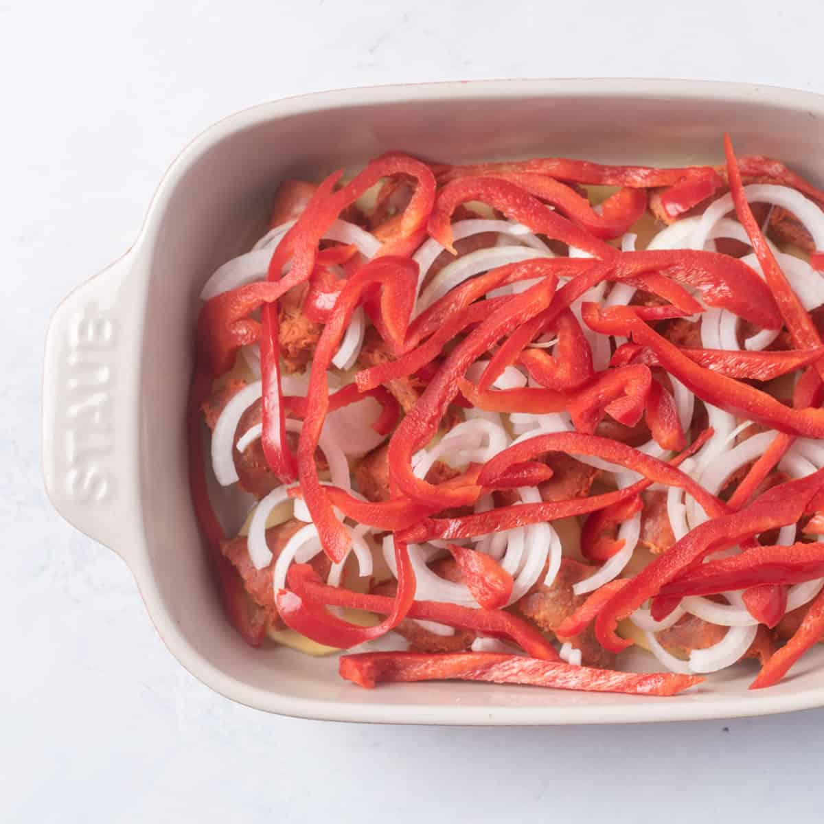 layers of potatoes, sausage, onions and red peppers in small baking dish
