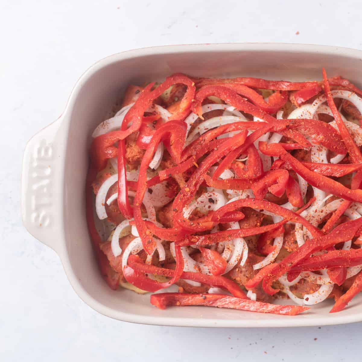 Layers of potatoes, sausage, onions and red peppers and sprinkles of red pepper flakes,in small baking dish