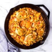 Chicken bouillabaisse stew in skillet on table.
