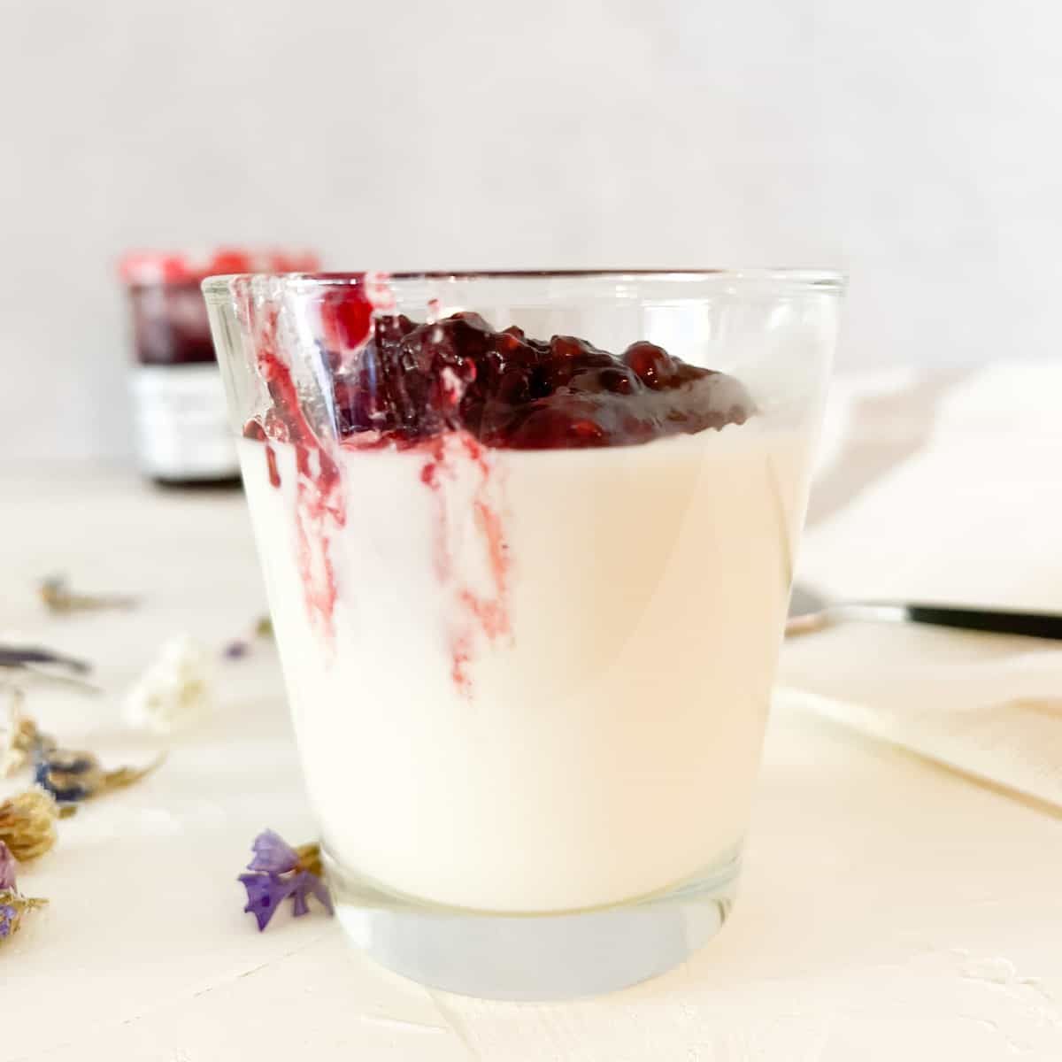Chilled dessert glass filled with Panna Cotta topped with jam.