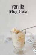 Vanilla cake in 8-ounce clear glass mug with spoon and strip napkin on table.