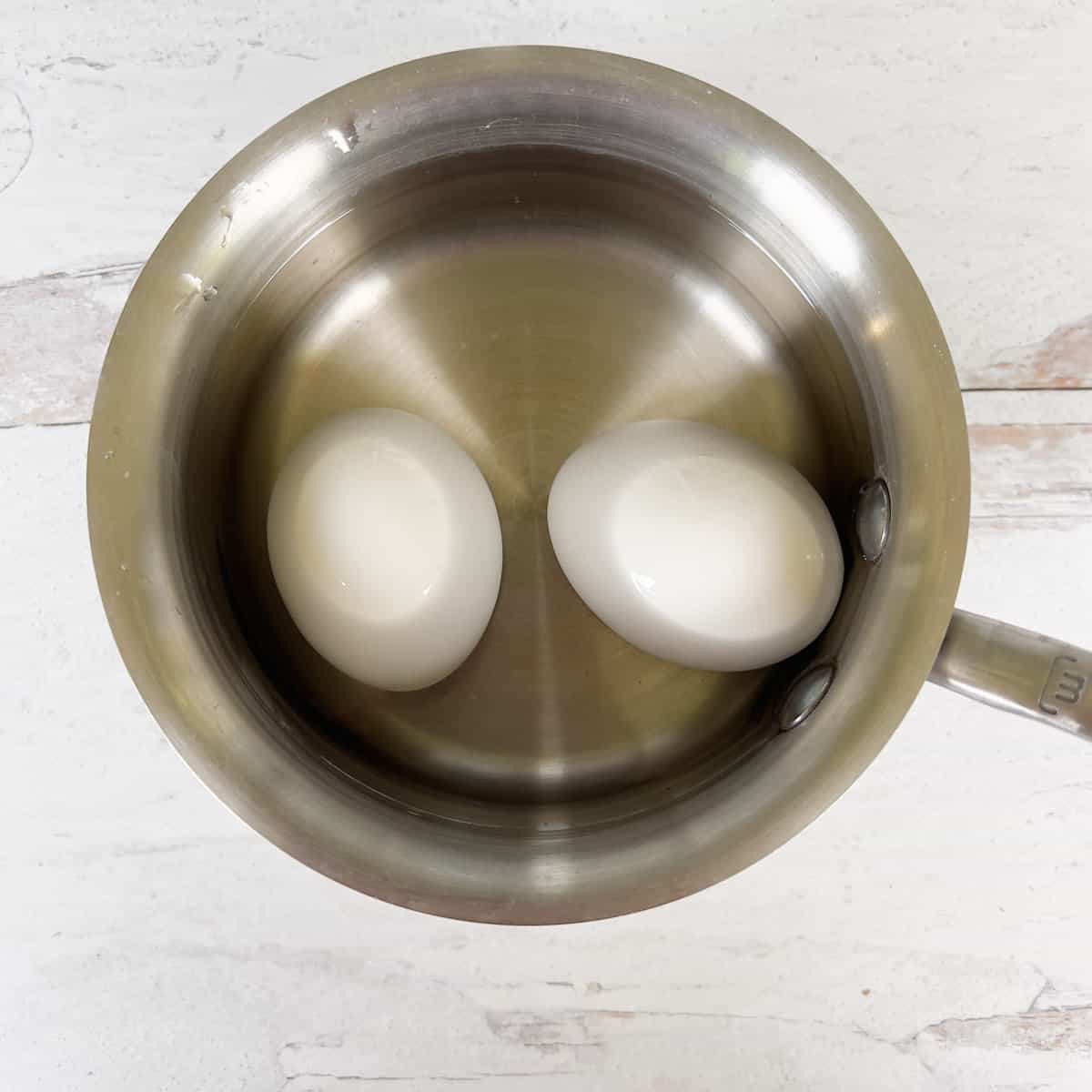 Two eggs boiling in saucepan.