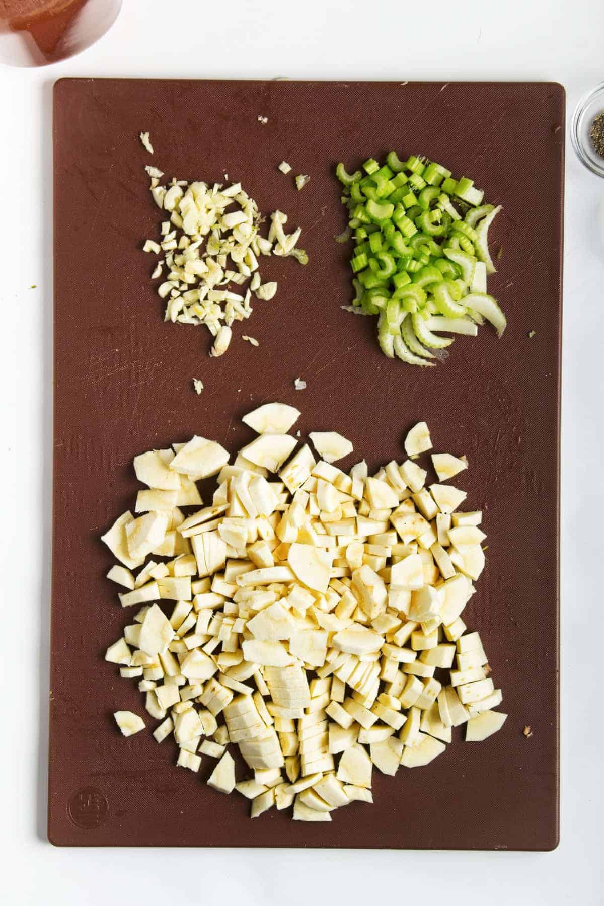 Parsnips, garlic, and celery chopped on cutting board.
