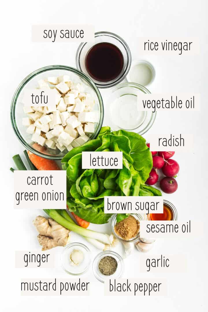 Diced tofu, vegetables, butter lettuce, and oils measured out on a white surface.