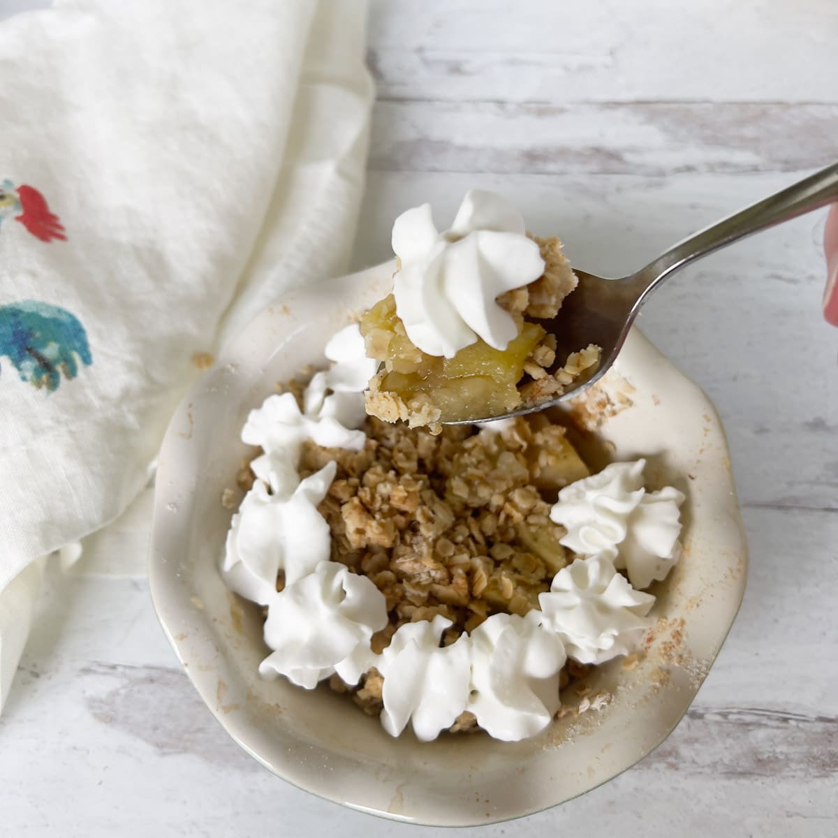Apple Crisp topped with whipped cream in a scalloped mini pie dish.
