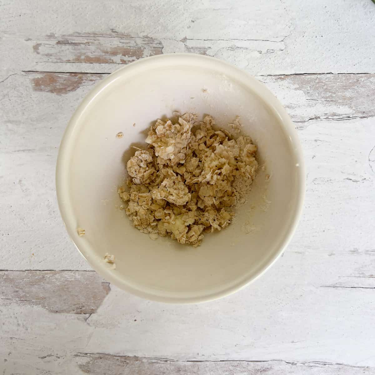 Rolled oats, butter, and flour mixed together in bowl.