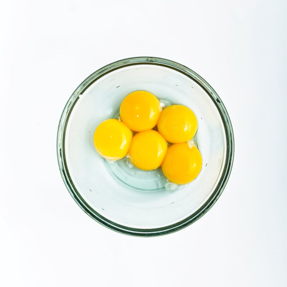 Five egg yolks in clear bowl.