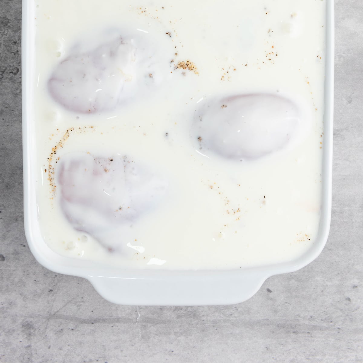 Chicken drumsticks in shallow dish covered with buttermilk.