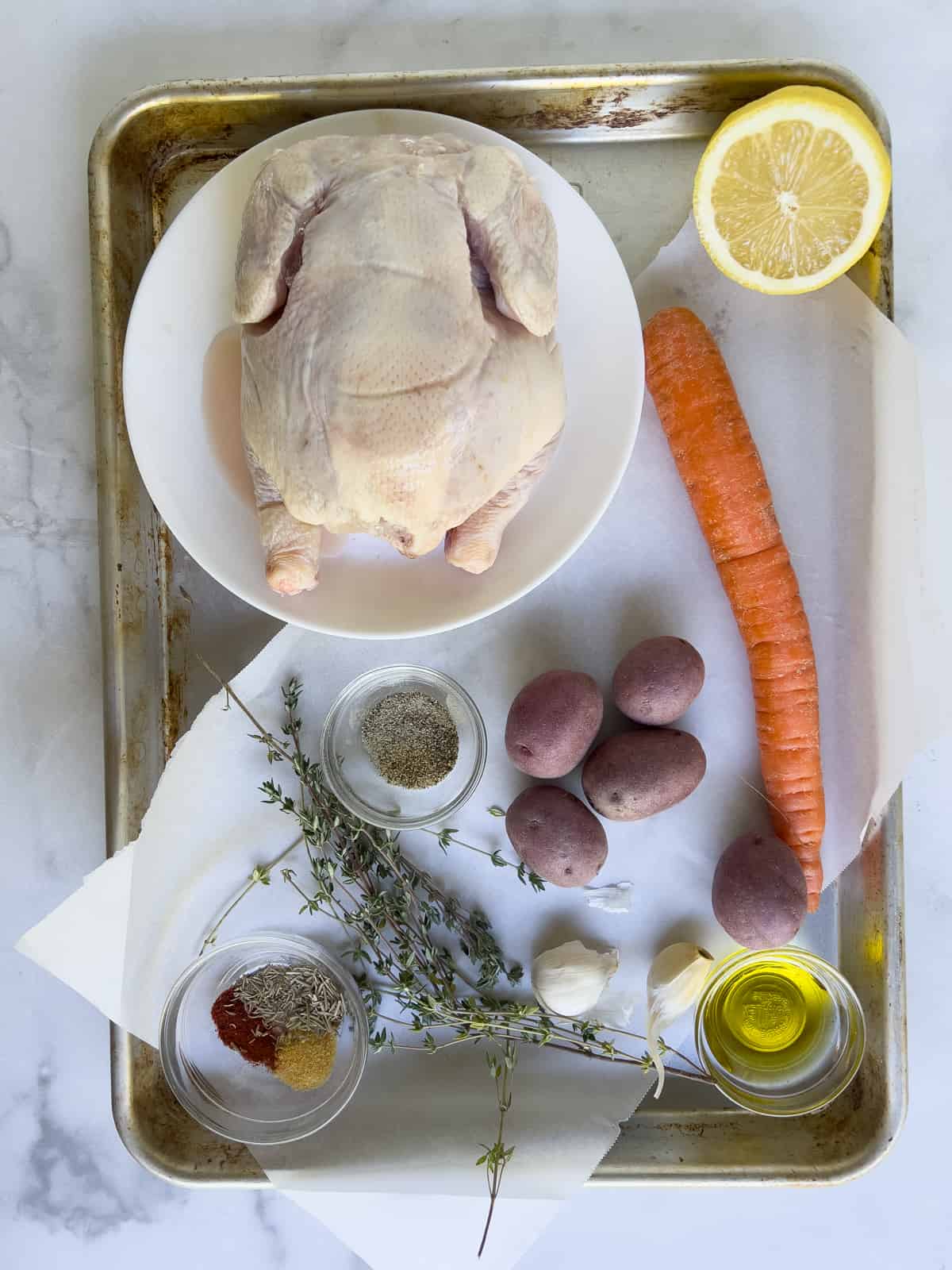 Uncooked cornish hen with herbs and spices on baking sheet.
