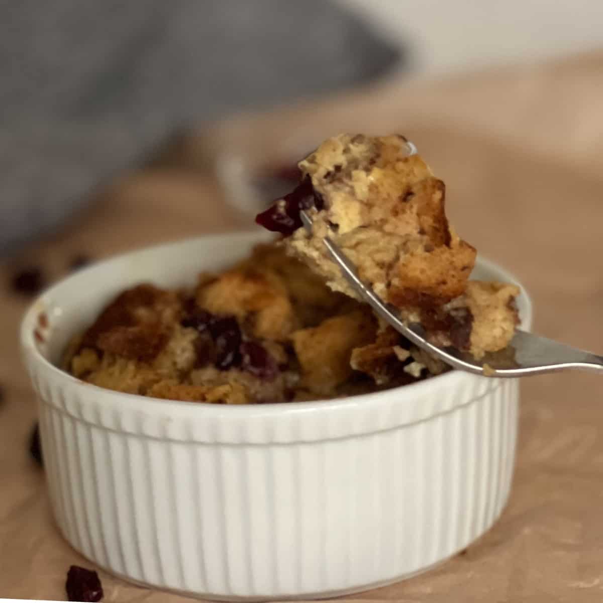Baked bread pudding in ramekin with forkful of bread pudding.