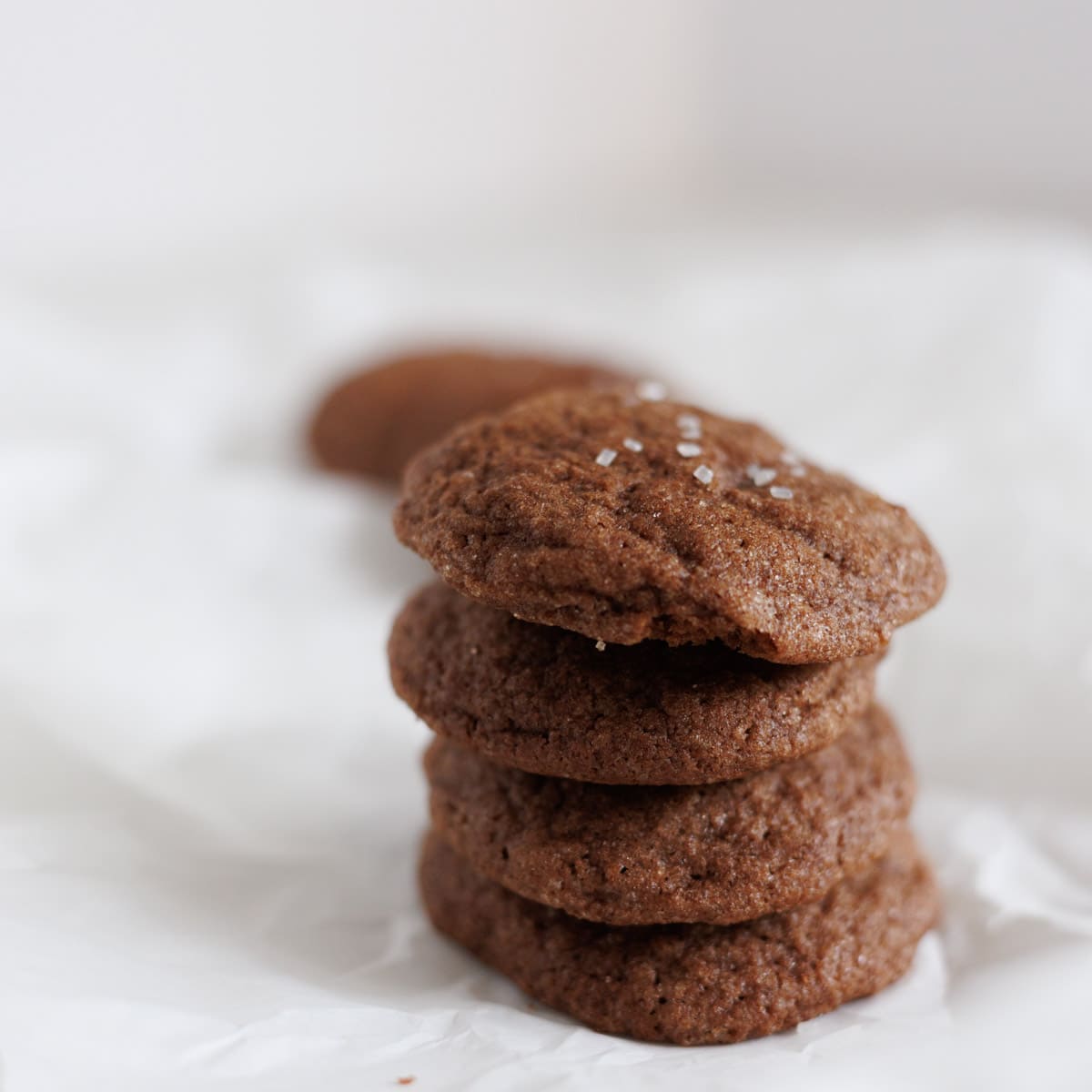 Chocolate Snickerdoodle cookies stacked on parchment paper.