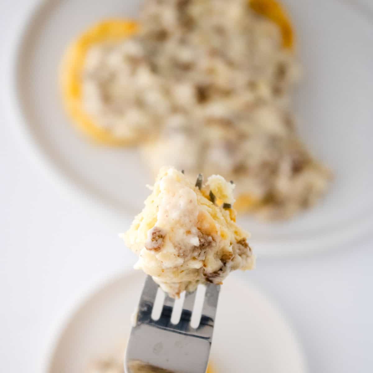 Homemade biscuits and gravy bite on fork.