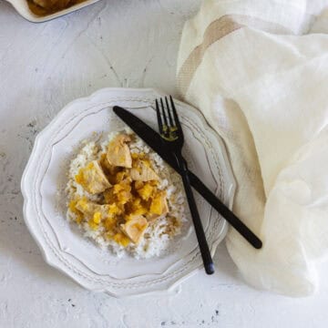 Pineapple chicken over a bed of rice on white plate.