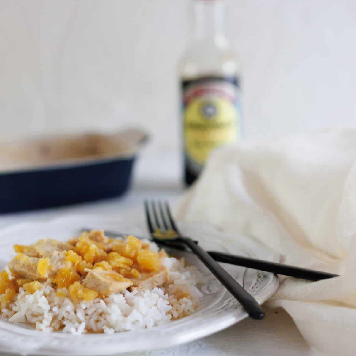 Pineapple chicken over bed of rice on white plate.