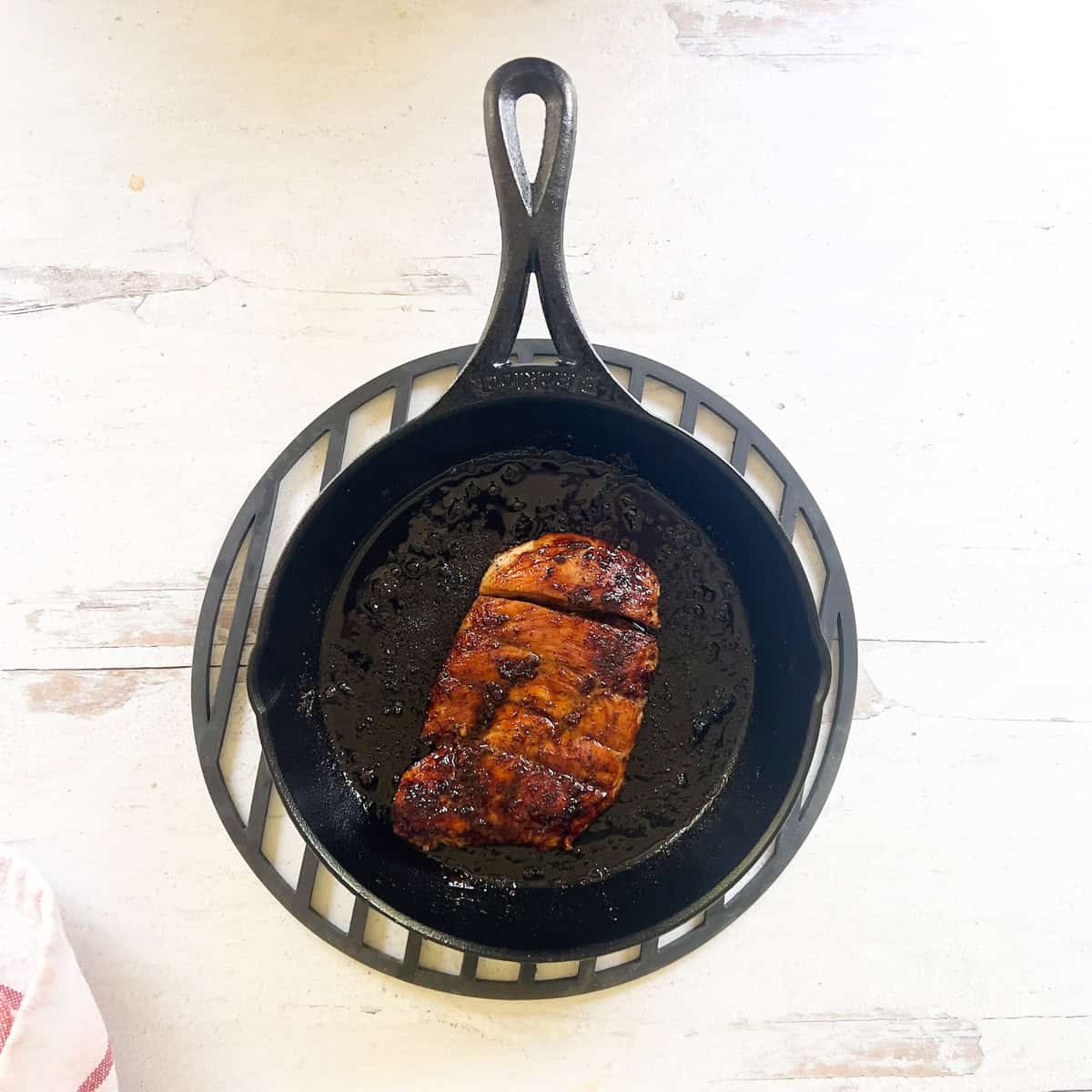 Chicken breast cooking in cast iron skillet.