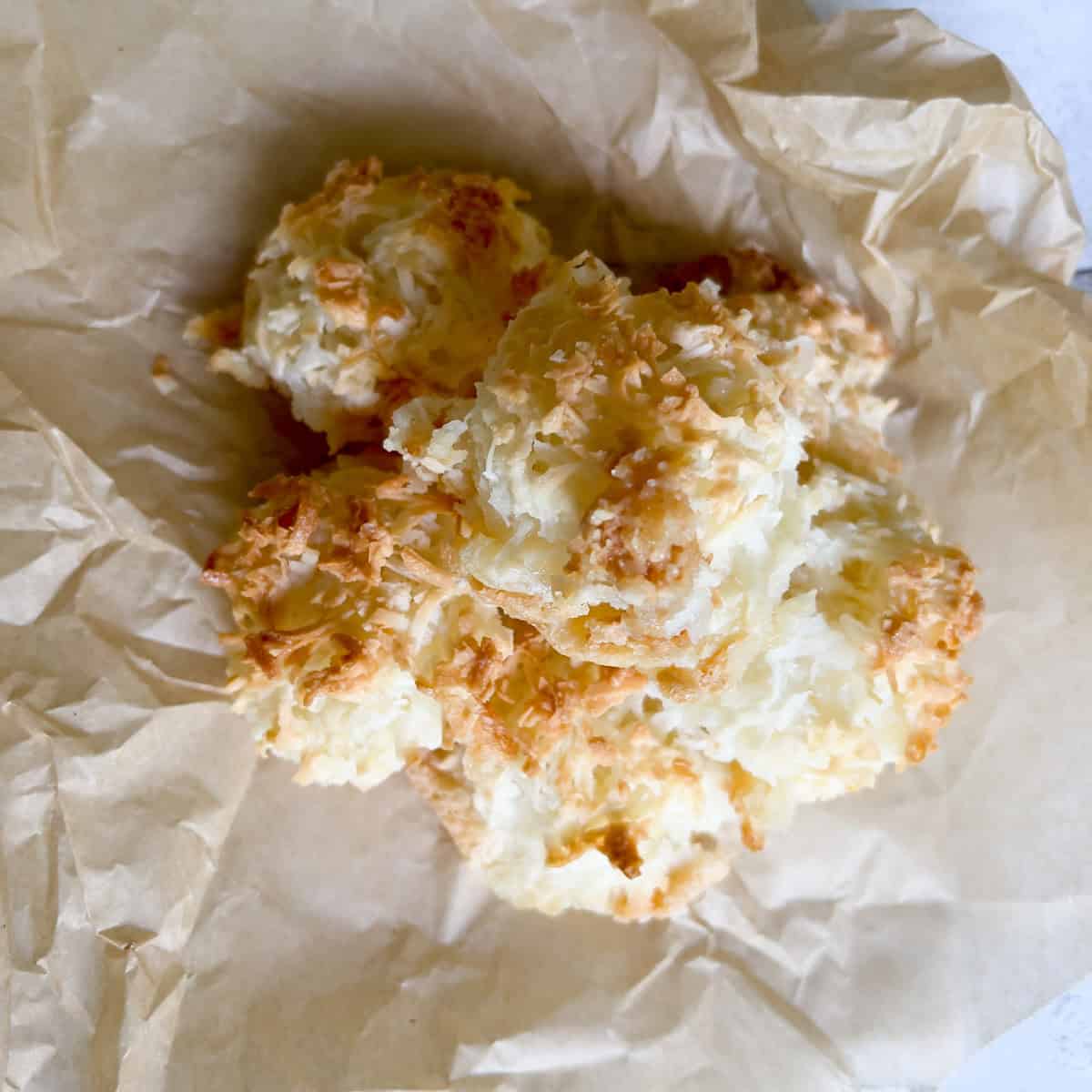 Stack of coconut macaroons on crumpled parchment paper.