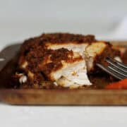 Maple chicken on sheet pan wioth bite on fork next to potatoes and carrots.