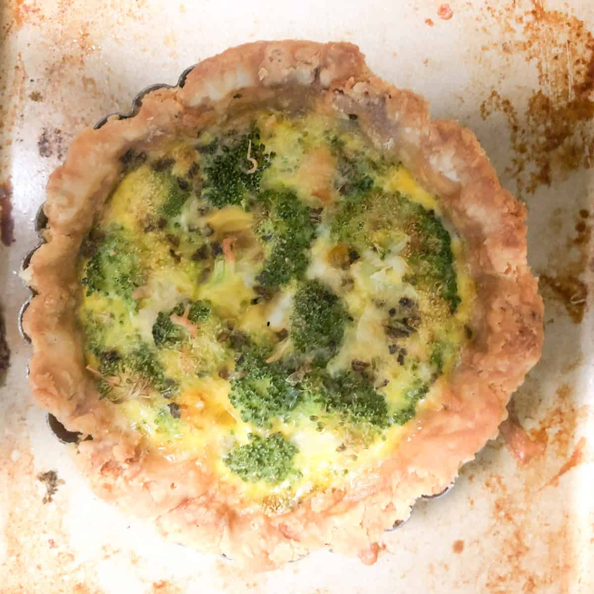 Homemade single serving quiche on baking sheet.