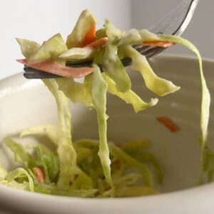 homemade coleslaw in white bowl with fork.