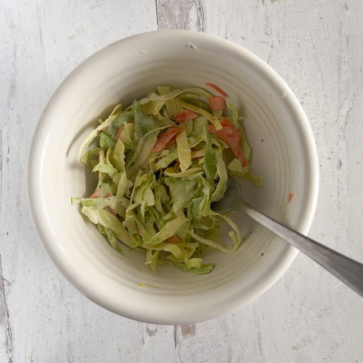 Homemade coleslaw in bowl with fork.