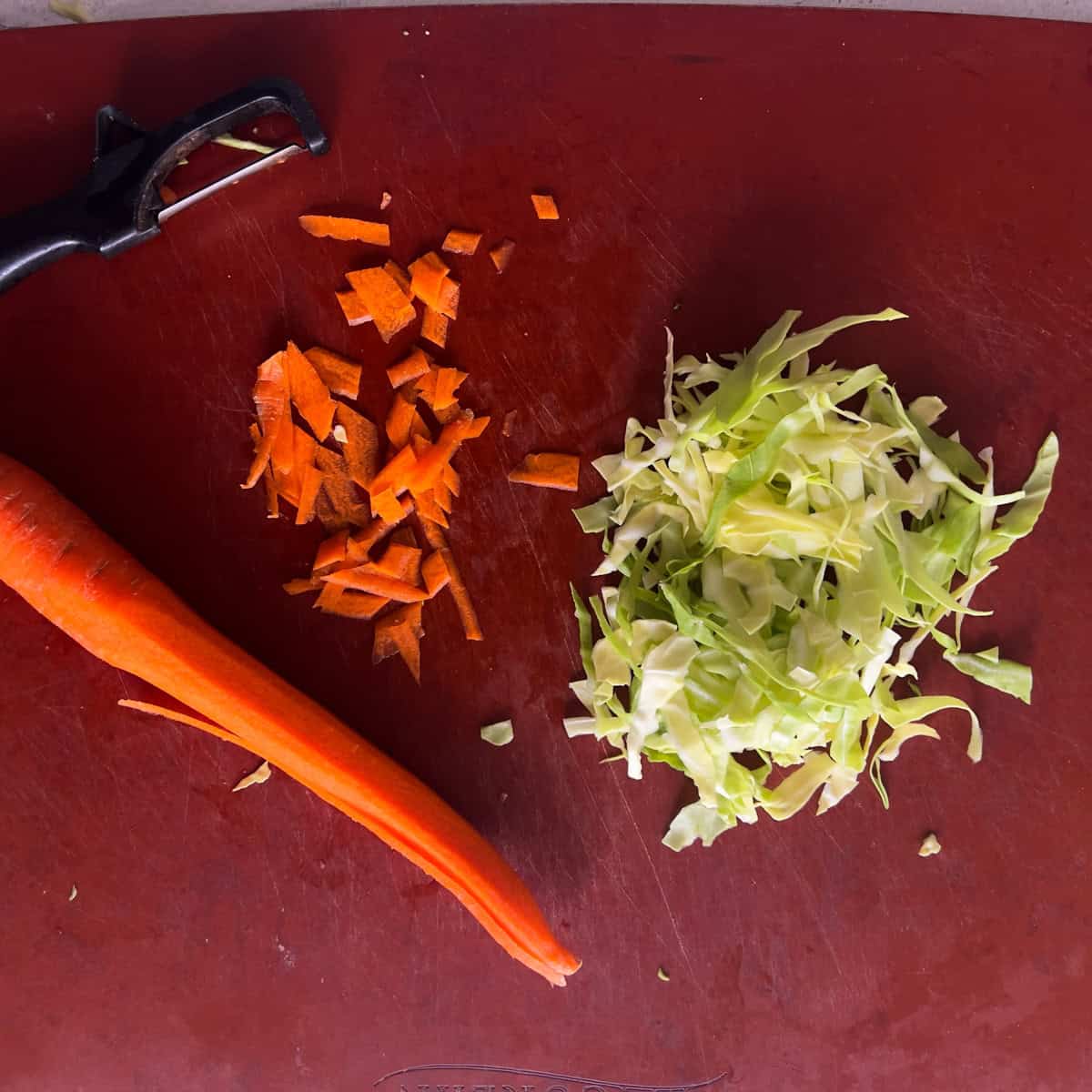 Chopped carrot and cabbage on cutting board.