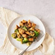 Plate of honey chicken and broccoli on a beige napkin.