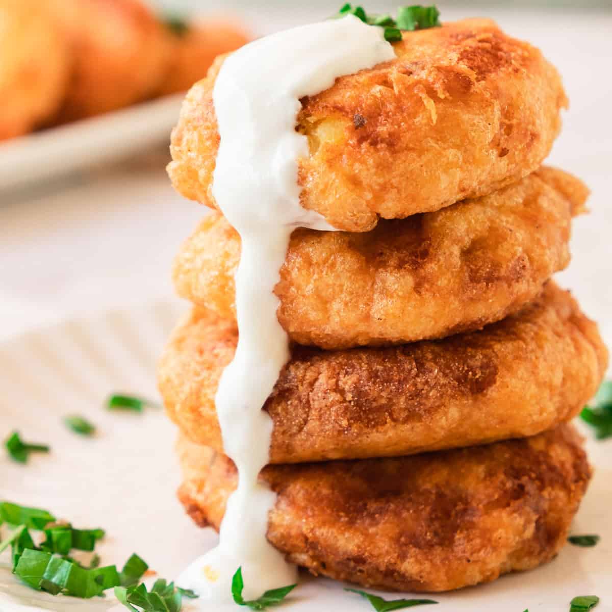 Stack of potato fritters with sour cream.