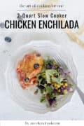 Chicken enchilada and green salad on plate.