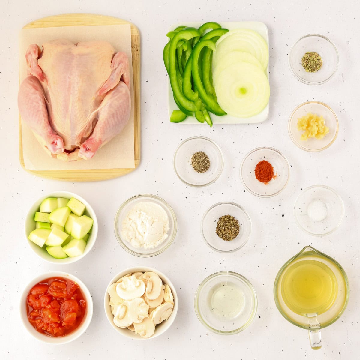 Cornish hen, vegetables, and seasonings on table.