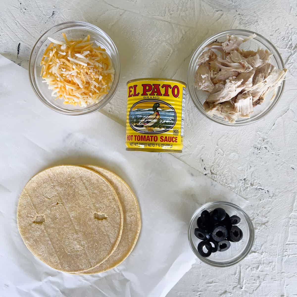 Shredded chicken, grated cheese, enchilada sauce, olives, and corn tortillas.