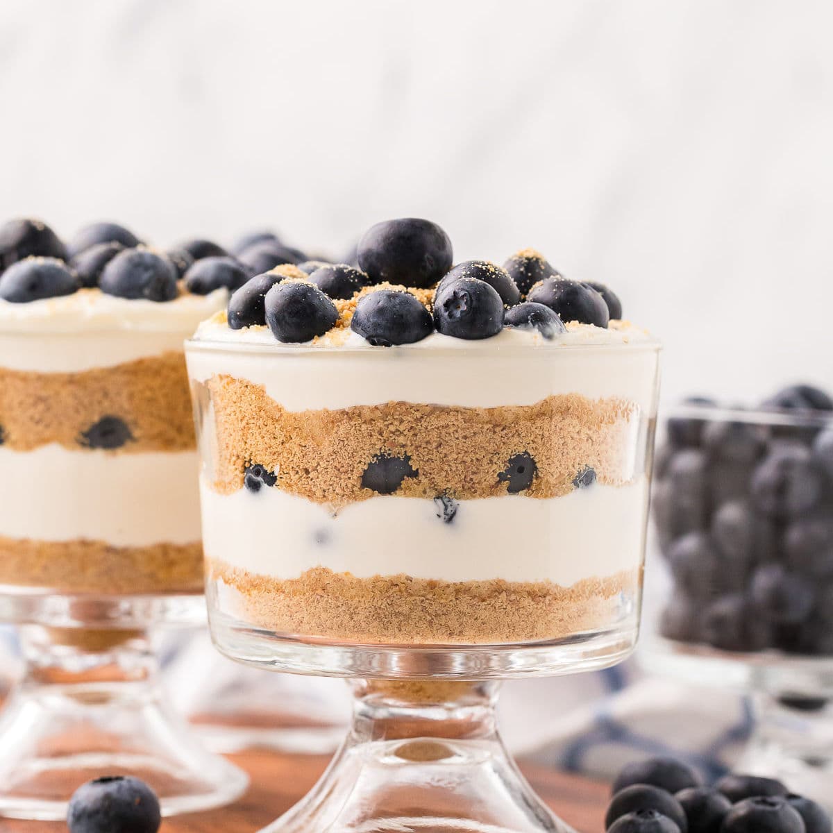 Mini blueberry parfaits with layers of cream, graham crumbs, and blueberries in glass dessert cups.
