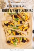 Sliced fruit and brie flatbread topped with peaches, blackberries, walnuts, and arugula on parchment paper.