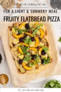 Flatbread pizza topped with peaches, blackberries, arugula, and walnuts on parchment paper, surrounded by ingredients.