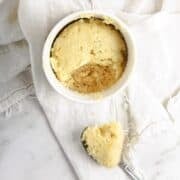 lemon cake in a mug with bite on spoon sitting on napkin.