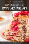 Stack of raspberry pancakes topped with fresh raspberries and syrup, with a fork pressed into layers of pancake with fresh raspberries beside.