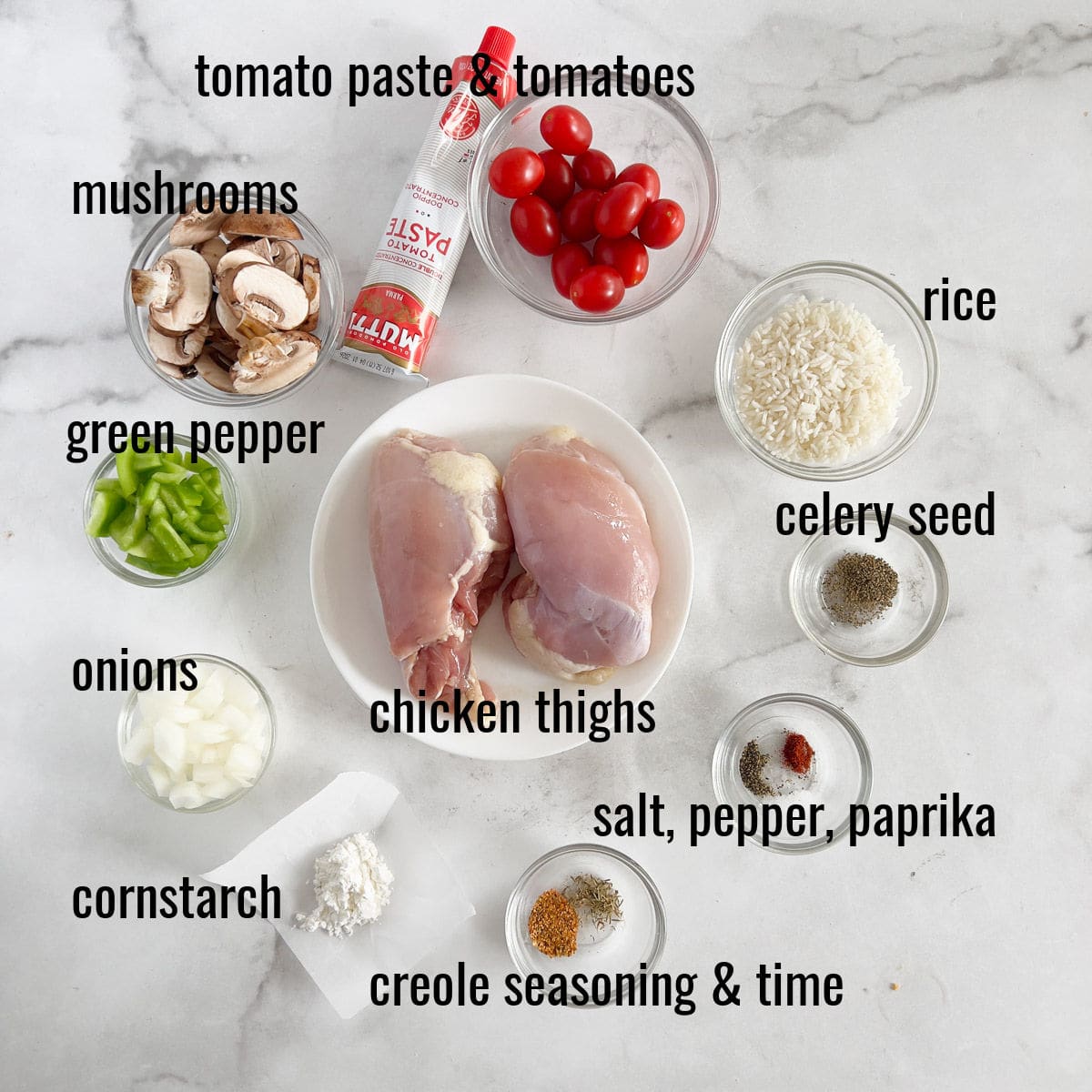 Ingredients for a recipe, including chicken thighs, vegetables, seasonings, rice, and cornstarch, labeled on a counter.