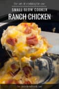 Small slow cooker with ranch chicken and portion on spatula.