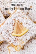 Close-up of powdered sugar-dusted lemon bars, each topped with a small lemon wedge. Text reads, Small Batch Lovely Lemon Bars.