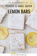 Overhead view of powdered sugar-dusted lemon bars on a white surface, surrounded by lemon slices. Text overlay: Classic & Small Batch Lemon Bars by aweekendcook.com.