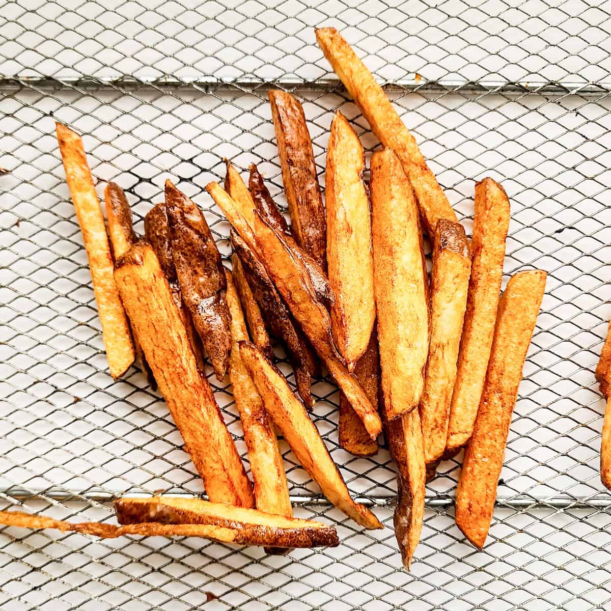Golden brown garlic fries scattered on a metal wire rack, made in a small batch for the perfect crispy treat.